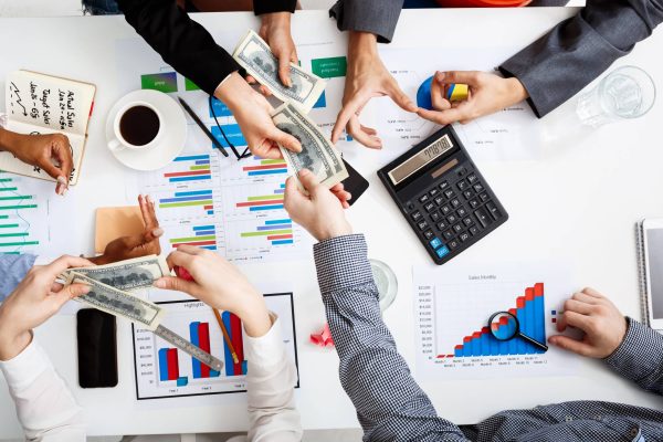 Picture of businessmen's hands on white table with documents, coffee and drafts